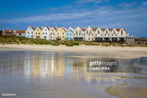 row of houses and a hotel, reflected in the water at braye beach, alderney, guernsey, channel islands - guernsey stock pictures, royalty-free photos & images