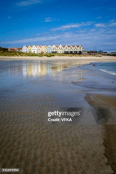 row of houses and a hotel, reflected in the water at braye beach, alderney, guernsey, channel islands - island of alderney stock pictures, royalty-free photos & images