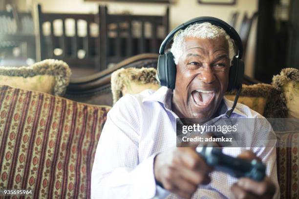 senior black man playing video games with headphones - playful joking home stock pictures, royalty-free photos & images