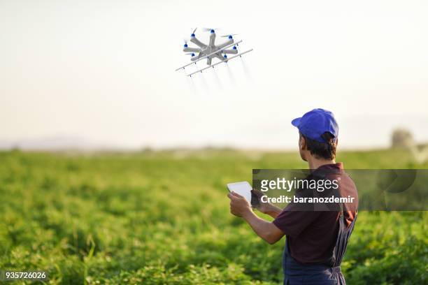 farmer spraying his crops using a drone - ponto de vista de drone imagens e fotografias de stock
