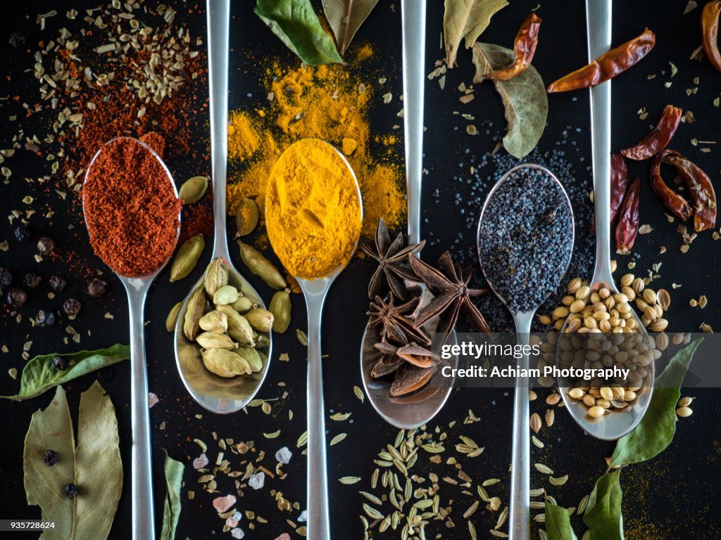 Spices on spoon against black background