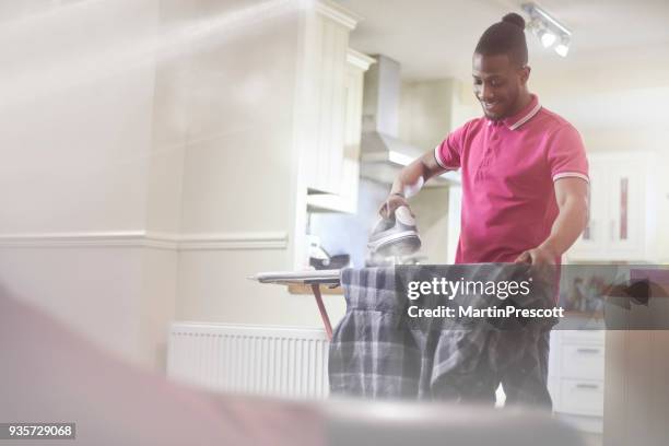 smiling male doing the ironing - ironing stock pictures, royalty-free photos & images