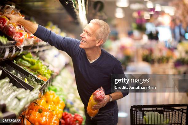 senior man goes grocery shopping. - customer choice stockfoto's en -beelden