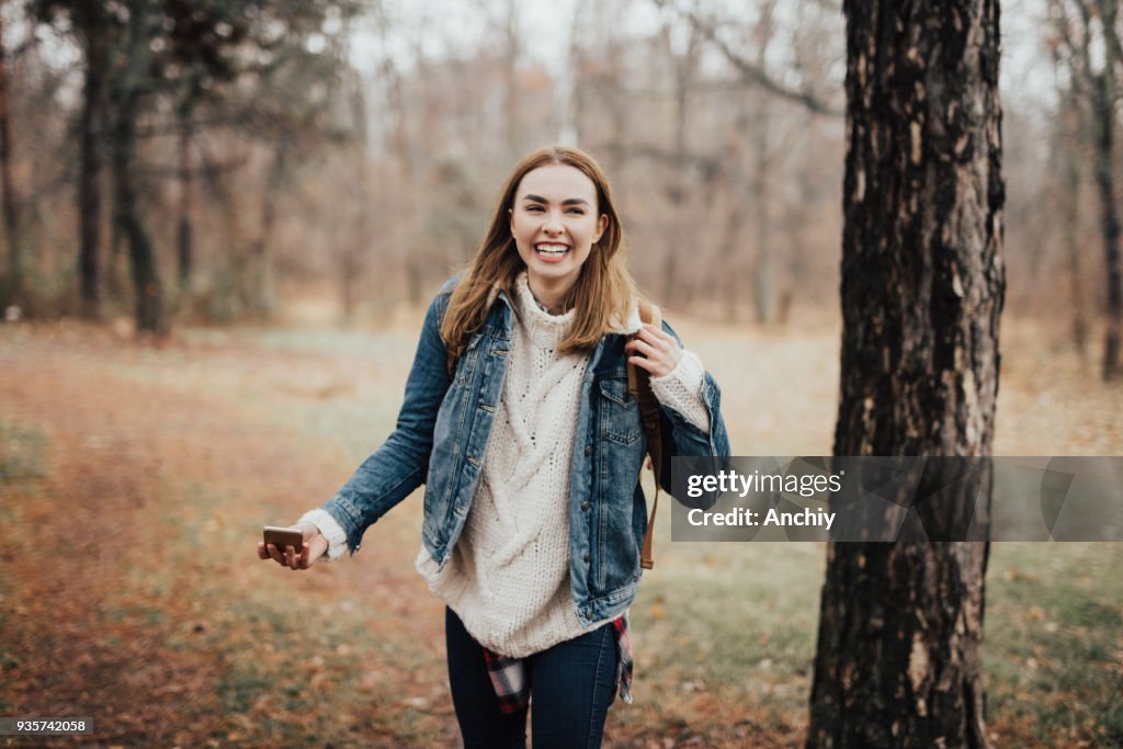 Glückliche junge Frau im Wald beim Blick in die Kamera Lächeln