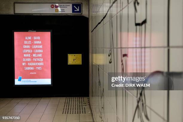 An advertising board shows the names of victims of the 2016 terrorist attacks in Brussels as a tribute, on March 21, 2018 at the Maalbeek - Maelbeek...