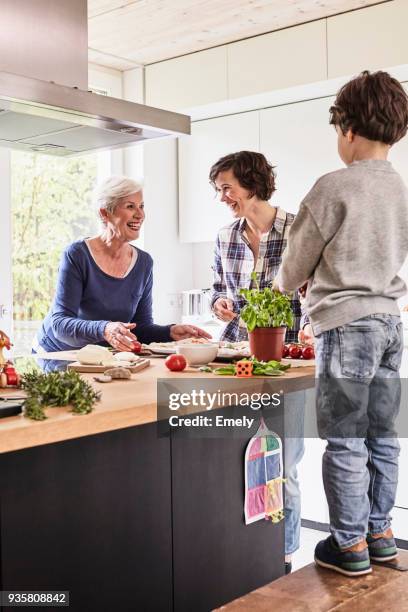 young boy, mother and grandmother making pizza together in kitchen - old person kitchen food stock-fotos und bilder