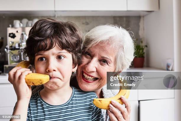grandmother and grandson fooling around, using bananas as telephones, laughing - banana woman photos et images de collection