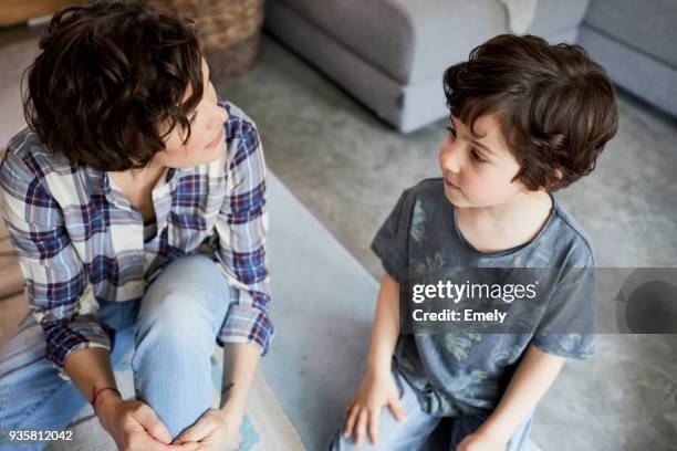 mother and son at home, sitting on floor, talking - kind im grundschulalter stock-fotos und bilder
