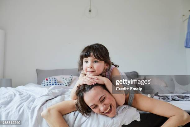 mother and daughter lying on bed, daughter lying on mothers back - 5 years stock pictures, royalty-free photos & images