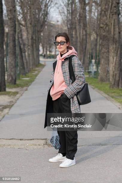 Fashion blogger for number-93 Sylvia Haghjoo wears a Céline bag and sunglasses, Burberry coat, Acne hooded sweater, Stella McCartney trousers and...