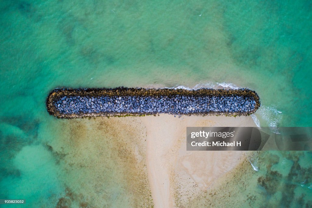Aerial view of blue sea and stone breakewater.