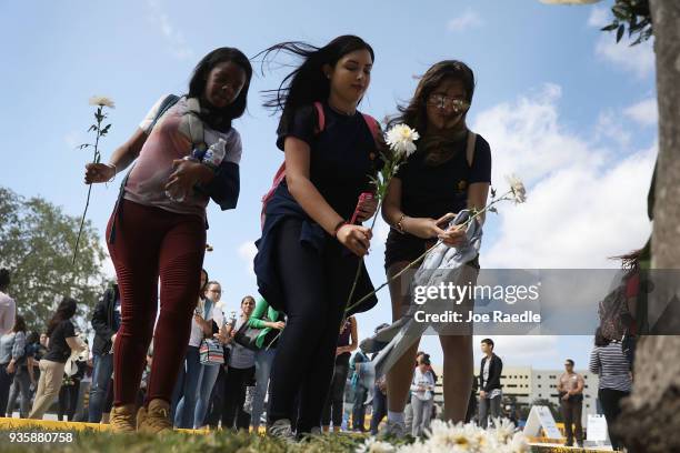 Friends, family, Florida International faculty and students lay flowers at a makeshift memorial as they mourn together during a vigil for victims of...