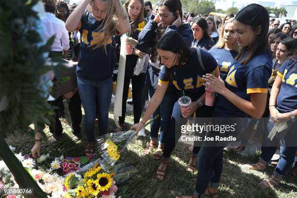 Friends, family, Florida International faculty and students lay flowers at a makeshift memorial as they mourn together during a vigil for victims of...