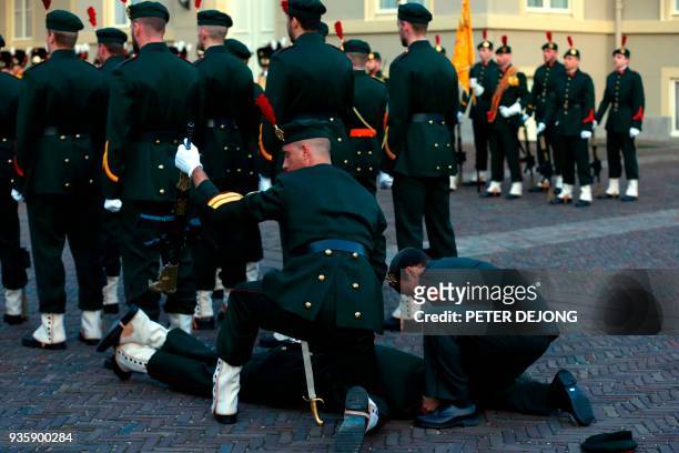 Member of honour guard is helped after collapsing, before the meeting of French President and Dutch King at royal palace Noordeinde in The Hague, on...