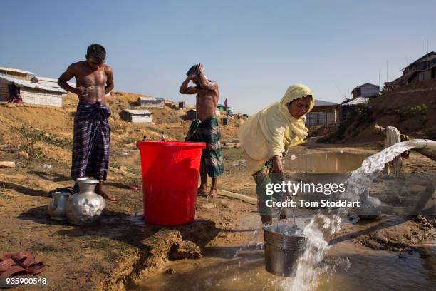 Rohingya woman collects water and men wash at a pipe in Kutupalong refugee camp on February 28, 2018 at Cox's Bazar, Bangladesh. Over 655,000...