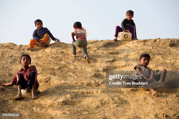 Rohingya children slide down a hill on plastic cannisters in Kutupalong refugee camp on February 26, 2018 at Cox's Bazar, Bangladesh. Over 655,000...