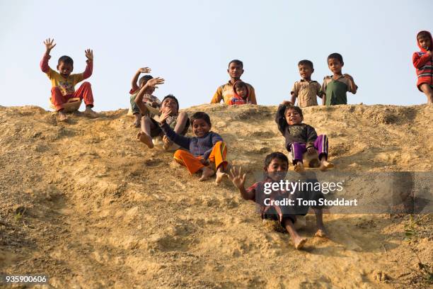 Rohingya children slide down a hill on plastic cannisters in Kutupalong refugee camp on February 26, 2018 at Cox's Bazar, Bangladesh. Over 655,000...