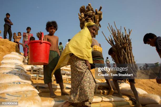 Rohingya people carrying firewood and water cannisters return home at the Kutupalong refugee camp on February 26, 2018 at Cox's Bazar, Bangladesh....