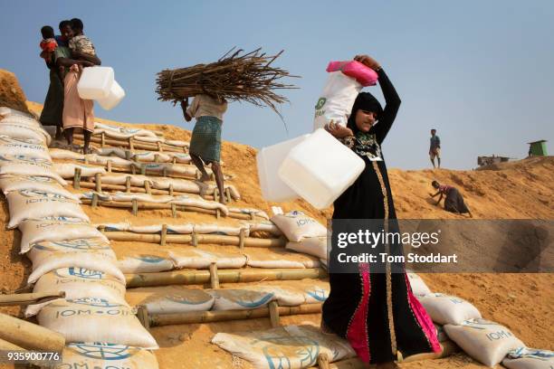 Rohingya people carrying firewood and water cannisters return home at the Kutupalong refugee camp on February 25, 2018 at Cox's Bazar, Bangladesh....