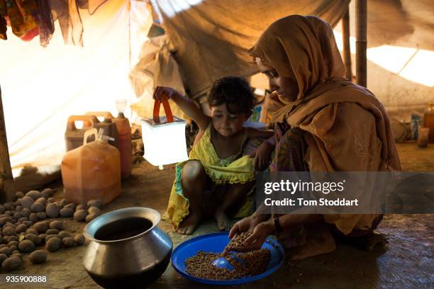 Rohingya mother prepares a meal for her family with the help of a solar light provided by Shelterbox UK at the Kutupalong refugee camp on February...