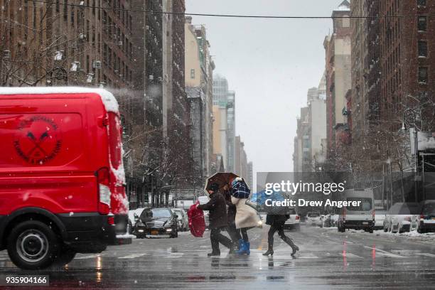 Pedestrians cross the street on Central Park West during a snowstorm, March 21, 2018 in New York City. The fourth nor'easter in three weeks hit the...