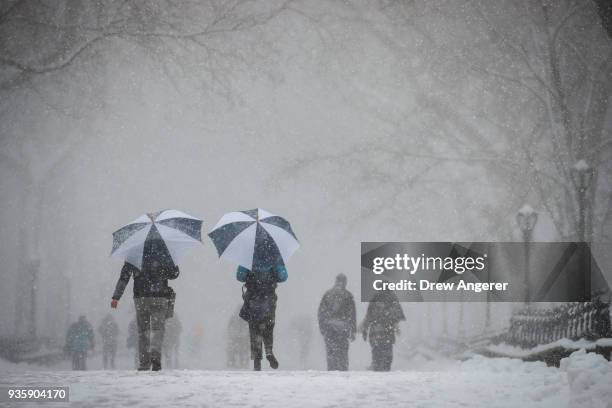 People carry umbrellas as they walk through Central Park during a snowstorm, March 21, 2018 in New York City. The fourth nor'easter in three weeks...