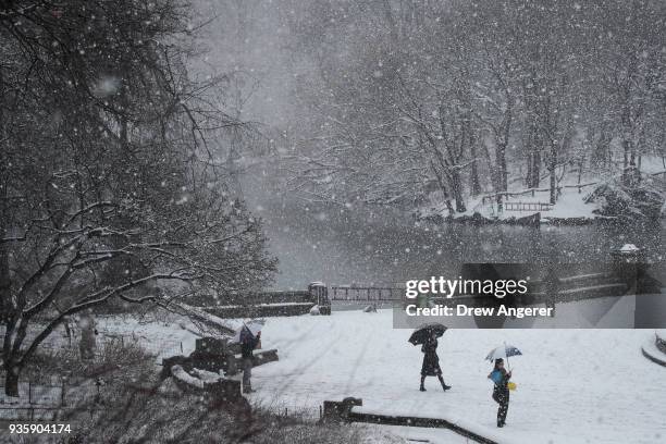 People walk near The Lake in Central Park during a snowstorm, March 21, 2018 in New York City. The fourth nor'easter in three weeks hit the city on...