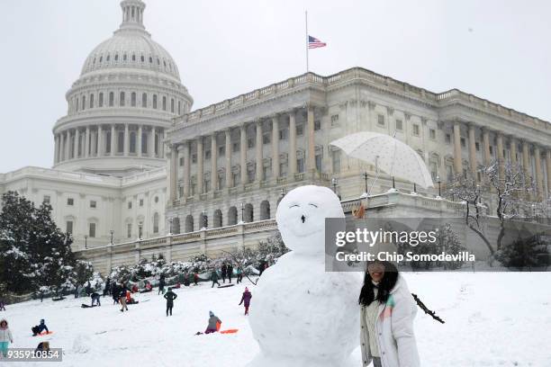 Tourist poses next to a 7-foot-tall snow man in front of the U.S. Capitol March 21, 2018 in Washington, DC. An early spring storm brought several...