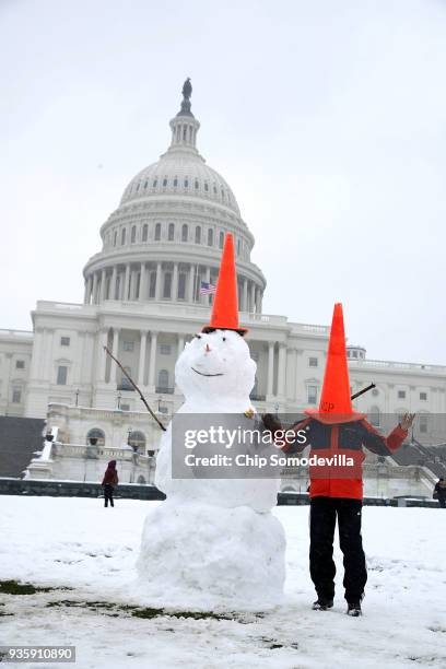 Man poses next to a 7-foot-tall snow man in front of the U.S. Capitol March 21, 2018 in Washington, DC. An early spring storm brought several inches...