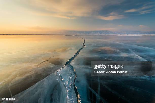 sunset on the ice with cracks. baikal, winter - cracked stock-fotos und bilder