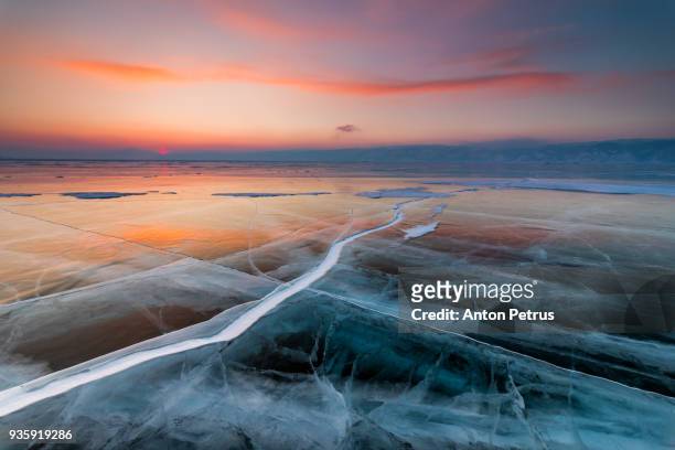 sunset on the ice with cracks. baikal, winter - baikal fotografías e imágenes de stock