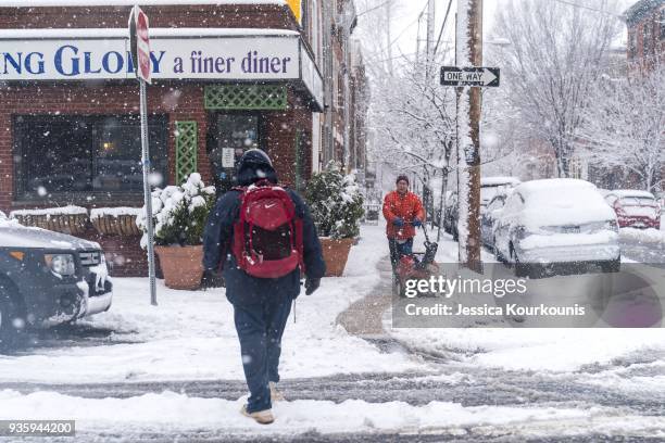 Man plows the sidewalk while people walk through snow on March 21, 2018 in Philadelphia, Pennsylvania. The fourth nor'easter in three weeks has...