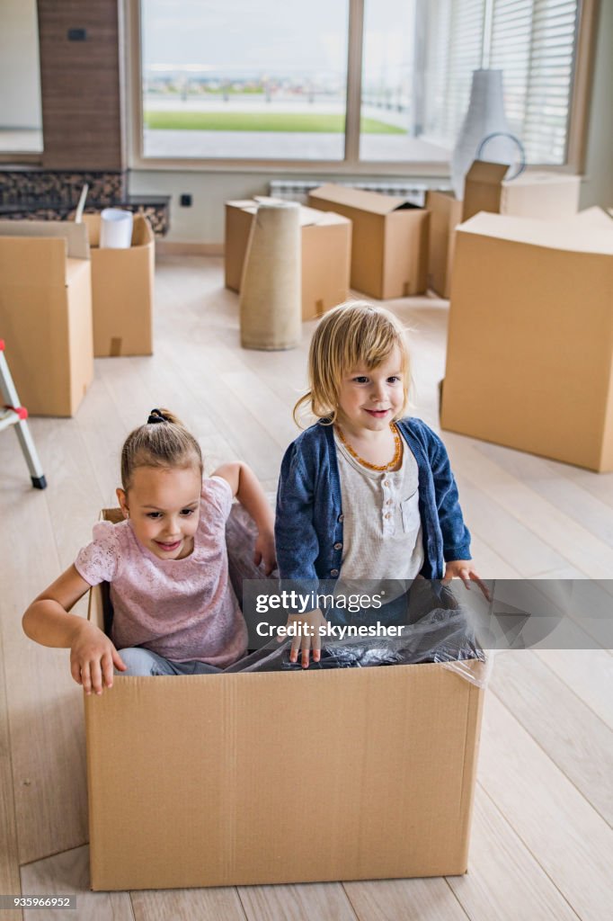 Playful brother and sister relocating into new apartment and having fun in carton box.