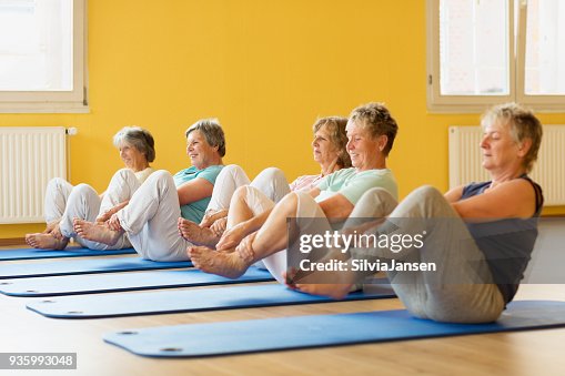 Group of active senior women in yoga class exercising on mat Group of active senior women in yoga class exercising on mat
