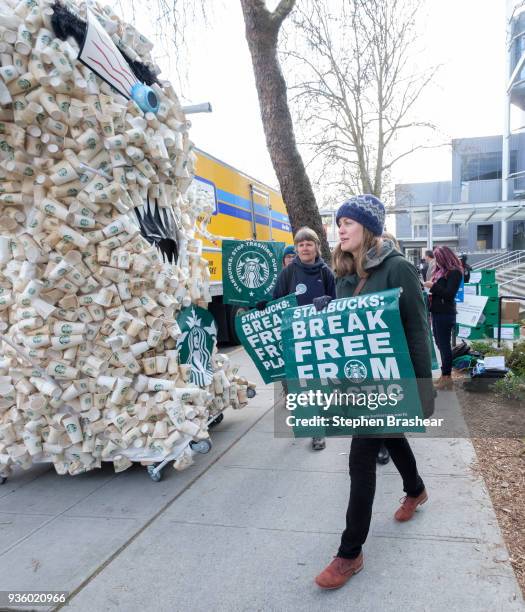 Protestor walks past a caricature made of coffee cups outside of the Starbucks Annual Shareholders Meeting at McCaw Hall, on March 21, 2018 in...