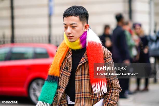 Guest wears a multicolor scarf, a checked tartan jacket during London Fashion Week February 2018 on February 18, 2018 in London, England.