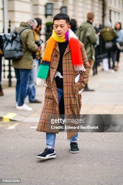 Guest wears a multicolor scarf, a checked tartan jacket, jeans, sneakers, during London Fashion Week February 2018 on February 18, 2018 in London,...