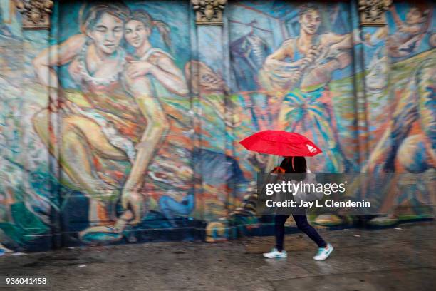 With a classic Boyle Heights neighborhood mural along Soto Street as a backdrop, Angelenos deal with a lingering rain storm over Los Angeles, CA,...