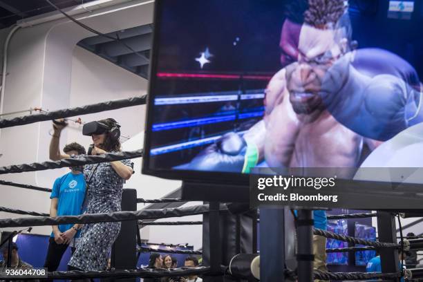 An attendee wears an Oculus VR Inc. Virtual reality headset while playing Creed, a game designed by Survios Inc., during the Game Developers...