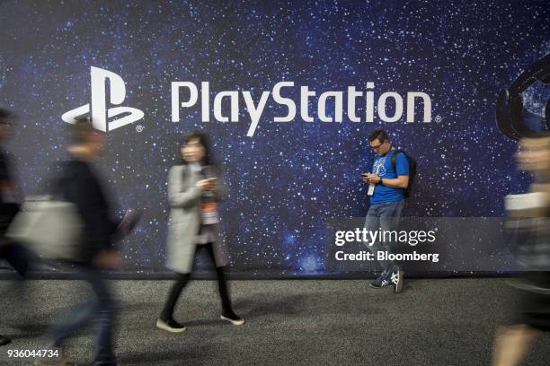 Attendees walk past Sony Corp. Playstation signage during the Game Developers Conference in San Francisco, California, U.S., on Wednesday, March 21,...
