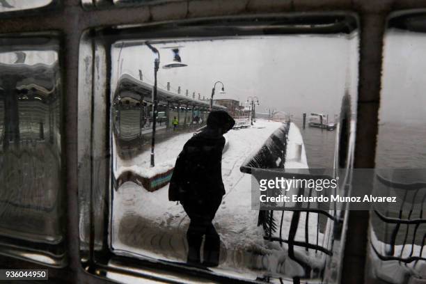 Man is seen through glass as he walks at the Hoboken train terminal during a snow storm on March 21, 2018 in Hoboken, New Jersey. At least 12 to 15...
