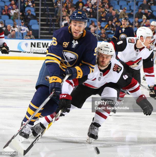 Justin Bailey of the Buffalo Sabres and Niklas Hjalmarsson of the Arizona Coyotes battle to control the puck during an NHL game on March 21, 2018 at...