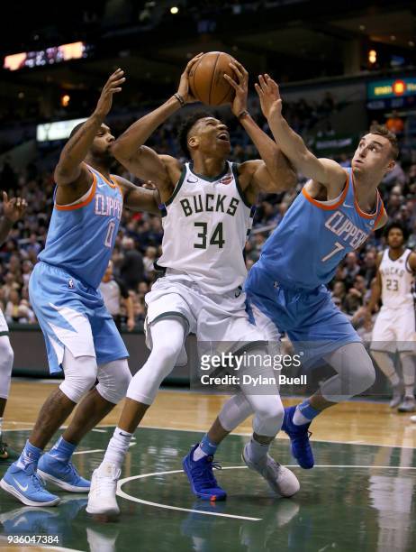 Giannis Antetokounmpo of the Milwaukee Bucks attempts a shot while being guarded by Sindarius Thornwell and Sam Dekker of the Los Angeles Clippers in...