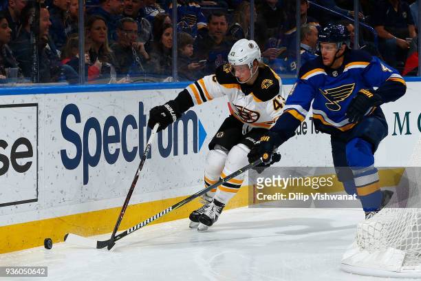 Danton Heinen of the Boston Bruins fights Carl Gunnarsson of the St. Louis Blues fro control of the puck at Scottrade Center on March 21, 2018 in St....