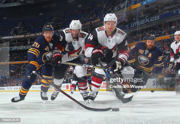 Scott Wilson of the Buffalo Sabres reaches for the puck against Alex Goligoski and Richard Panik of the Arizona Coyotes during an NHL game on March...