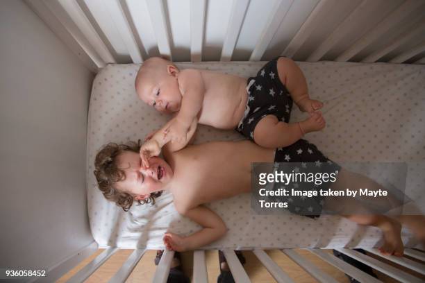 baby boy wakes up brother in the crib - annoying brother stock pictures, royalty-free photos & images