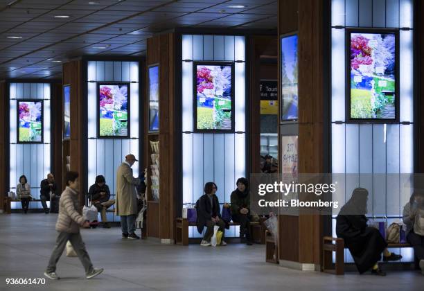 People sit on benches at the entrance to the Kanazawa station in Kanazawa, Japan, on Monday, March 19, 2018. Japan is scheduled to release February's...