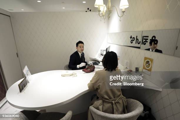 Inc. Employee, left, talks to a customer while appraising a handbag and a pair of shoes at the company's store in the Ginza district of Tokyo, Japan,...