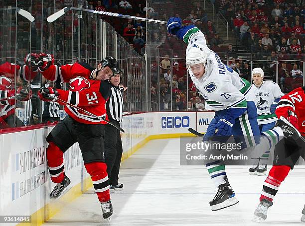 Mason Raymond of the Vancouver Canucks jumps to avoid a check by Matthew Corrente of the New Jersey Devils during their game at the Prudential Center...