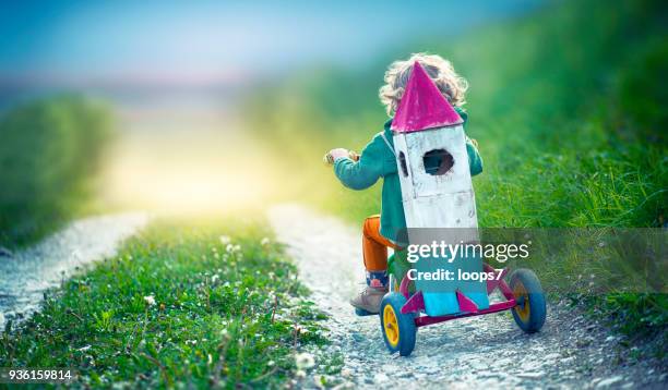 kind auf dem dreirad tragen eine weltraumrakete spielzeug - unschuld stock-fotos und bilder